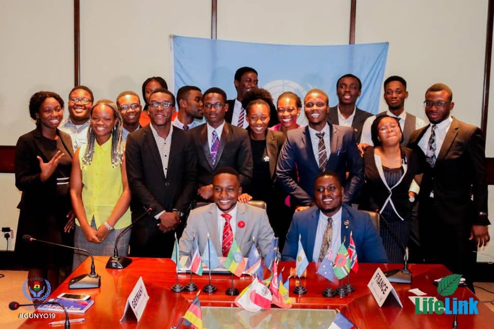 A group gathered under the United Nations flag.